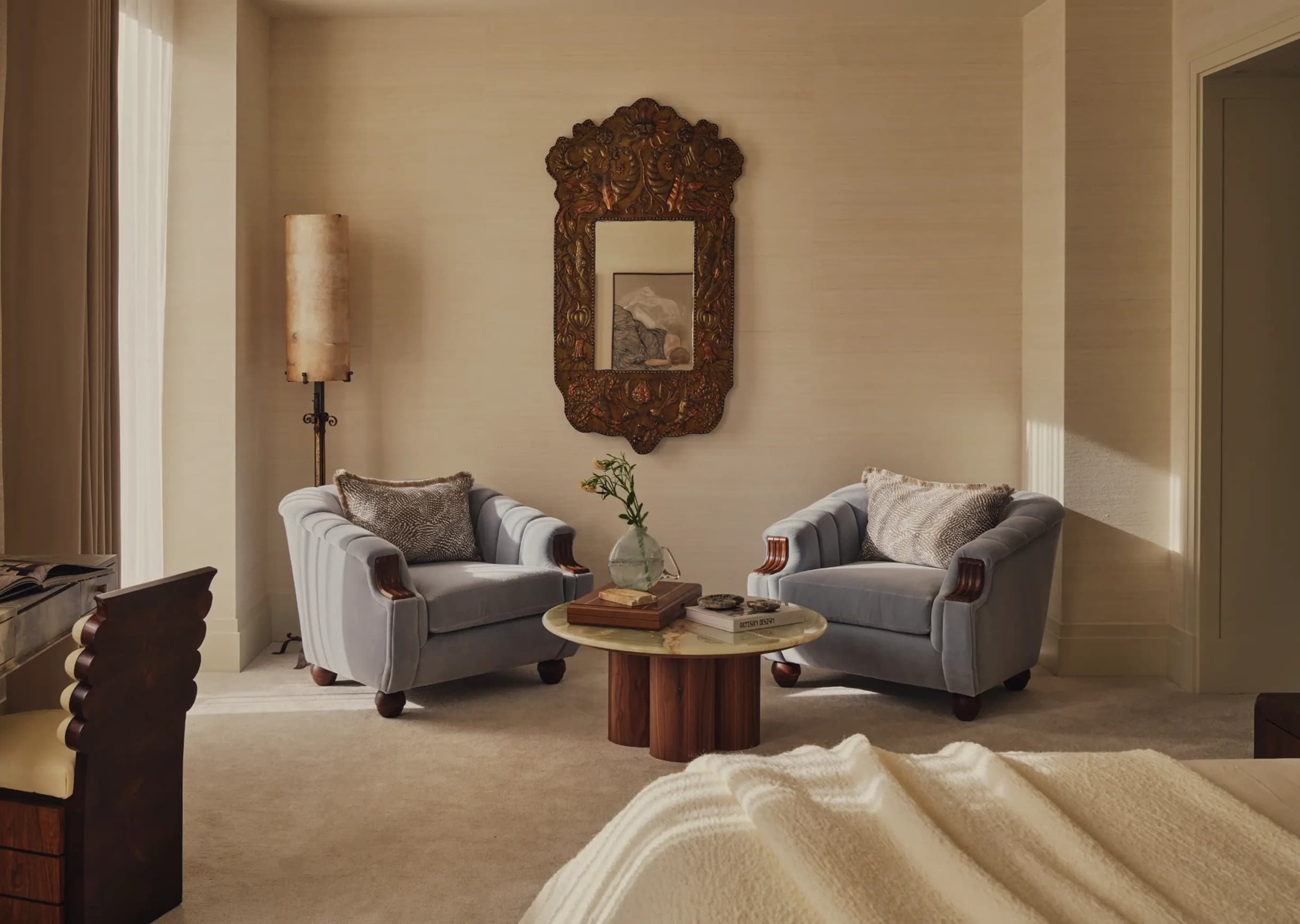 A sunlit East Toronto sitting room — two velvet armchairs, an onyx table and a carved mirror.